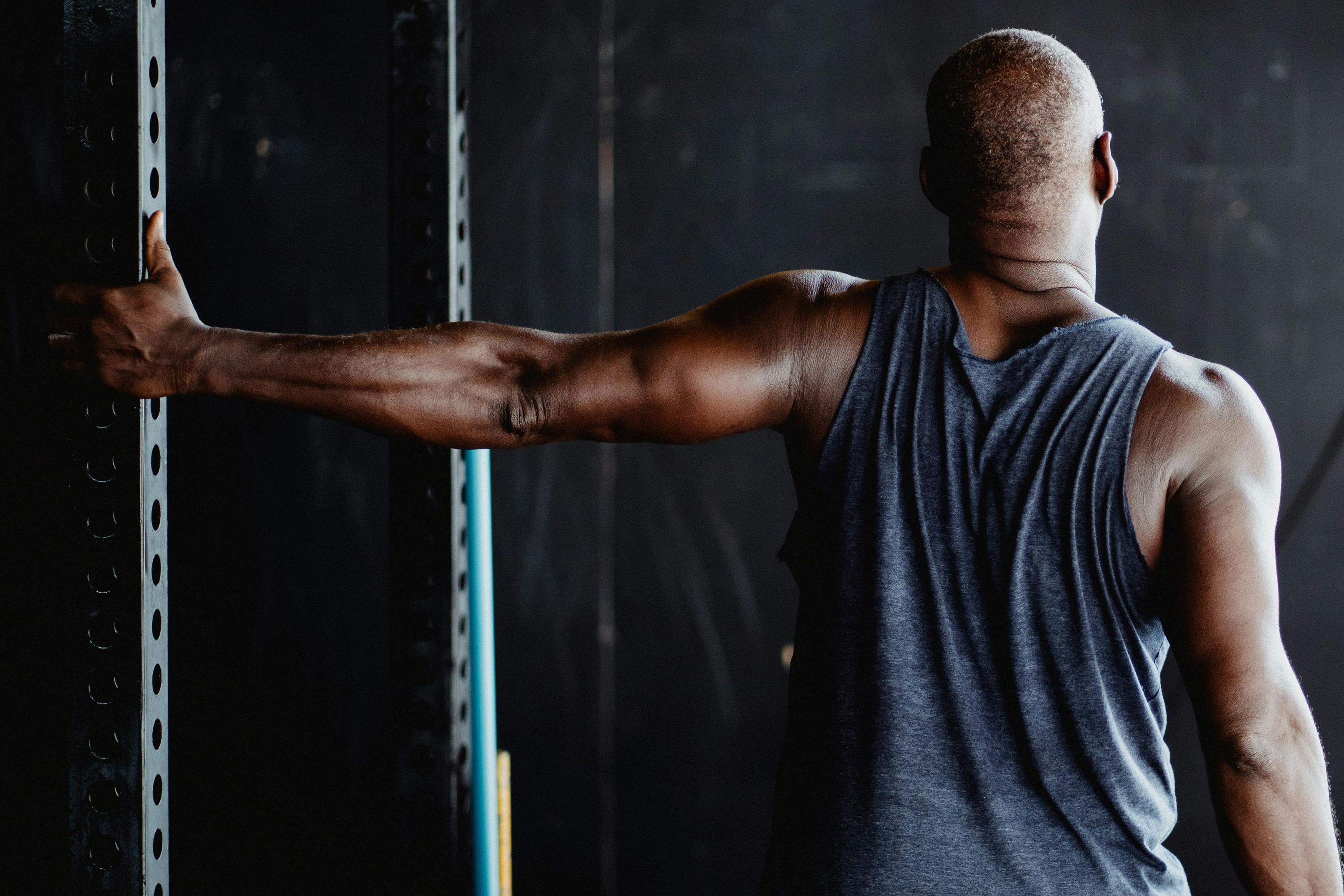 Man in a gym stretching his arm, chest, and shoulder