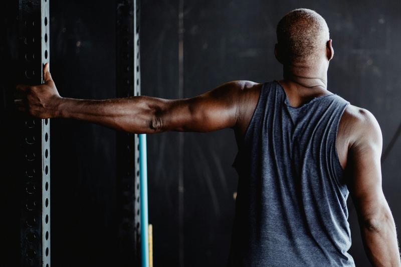 Man in a gym stretching his arm, chest, and shoulder